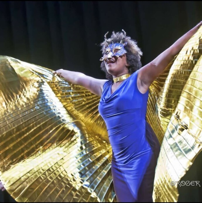 Debrissa performing in a blue dress with dramatic gold wings
